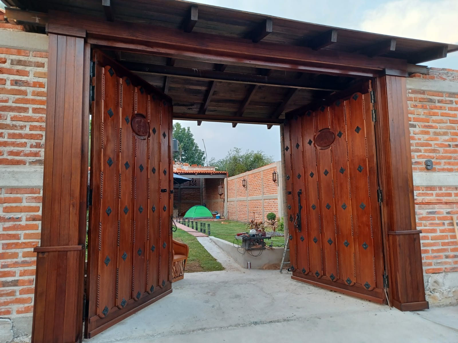 Portón de madera estilo rústico con talla artesanal y herrería de forja