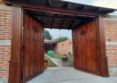 Porton de madera estilo rustico con talla artesanal y herreria de forja